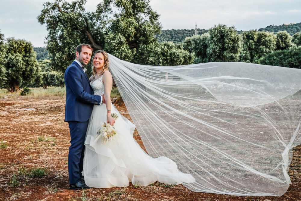 Scatto artistico velo lunghissimo sposa fluttuante nel vento in campagna