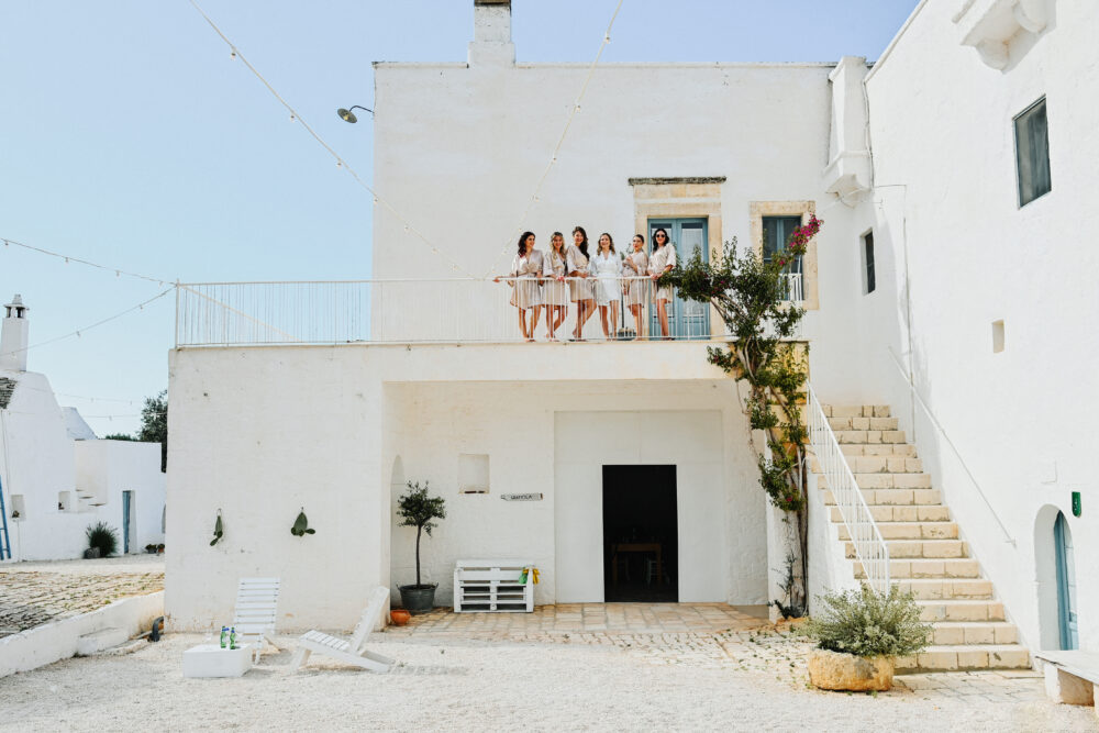 Foto di gruppo sposa e amiche sul terrazzo di una location bianca in Puglia