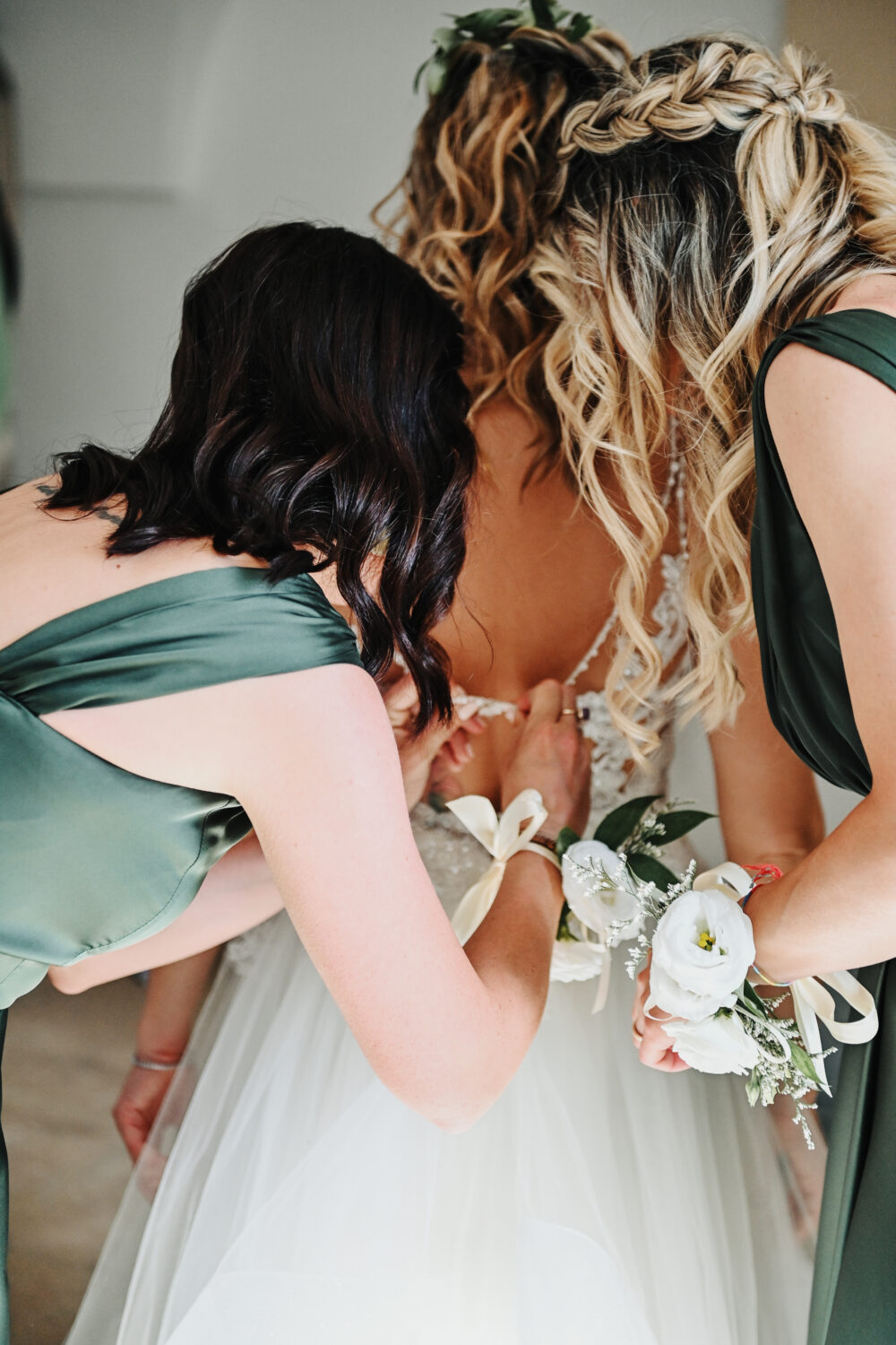 Dettaglio ricami abito da sposa e mani delle amiche della sposa
