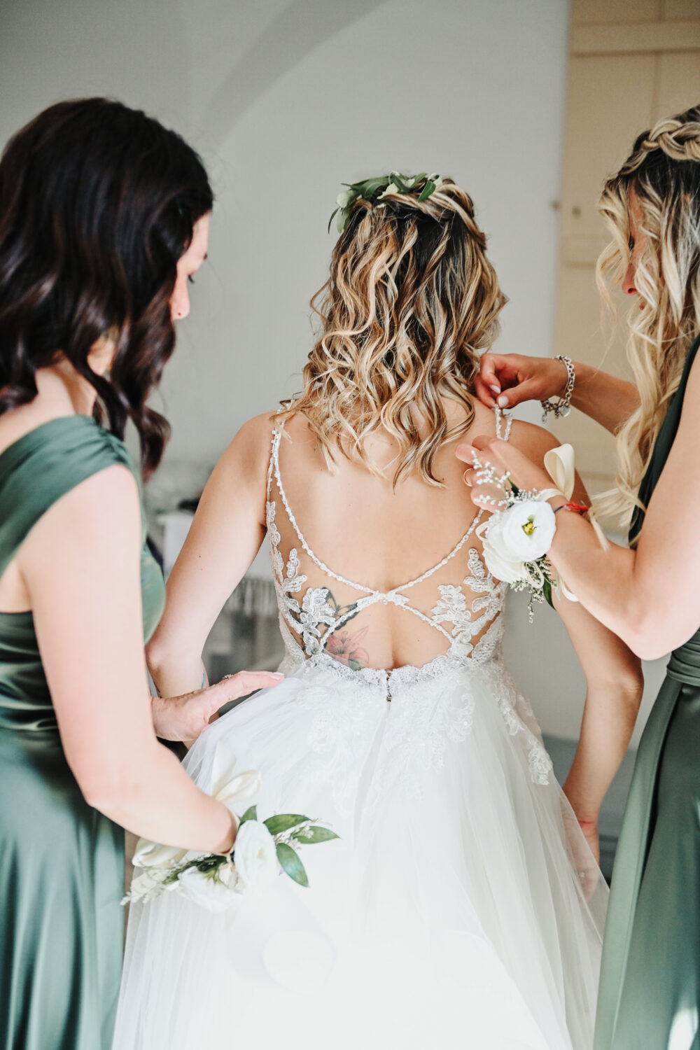 Damigelle aiutano la sposa a indossare il vestito prima del sì