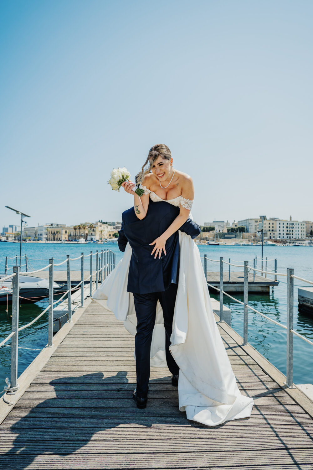 Sposo solleva la sposa sul pontile panoramico reportage di matrimonio
