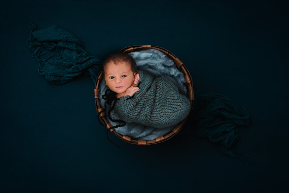 Servizio fotografico neonato posizionato nel cestino rustico in studio