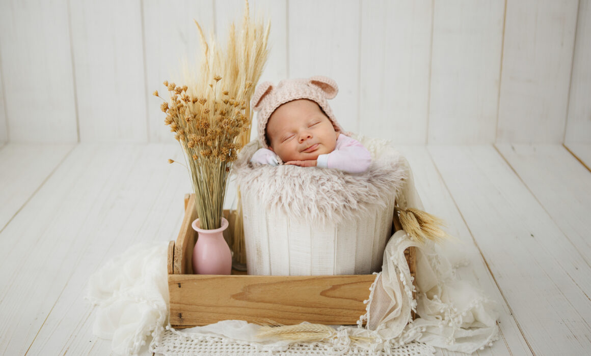 ervizio fotografico newborn in Puglia, neonato che dorme in un cestino di legno con cappellino