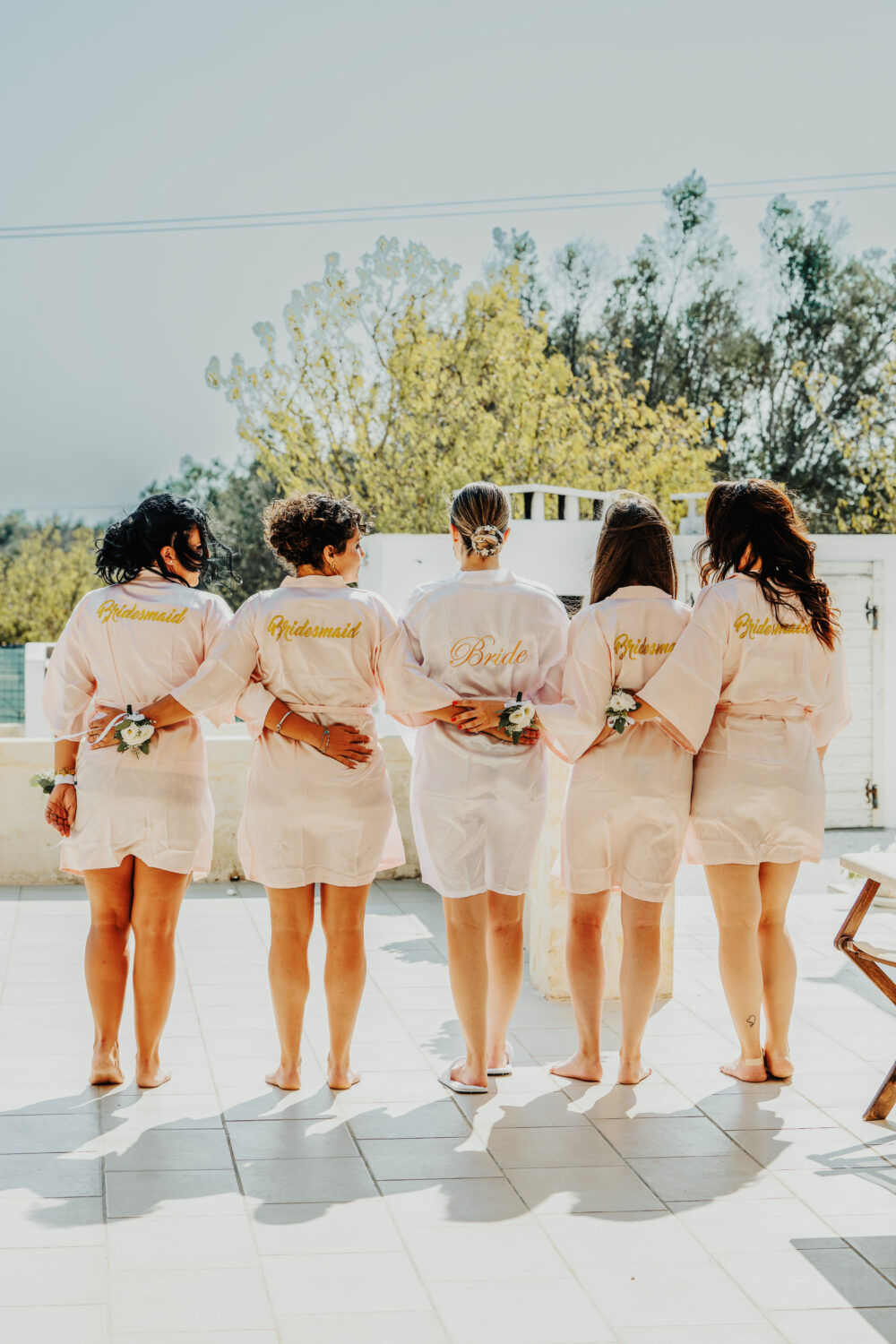 Sposa e damigelle in vestaglia brindano durante i preparativi di nozze