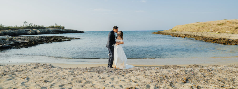 Sposi si baciano sul mare caletta rocciosa fotografo matrimonio Puglia