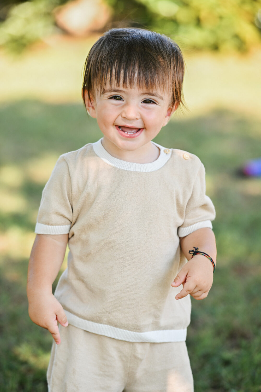 Scatto spontaneo bimbo sorridente sul prato servizio fotografico famiglia
