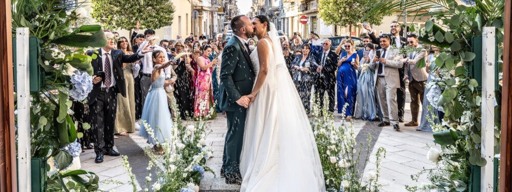 Uscita chiesa sposi bacio romantico sotto il lancio del riso Puglia