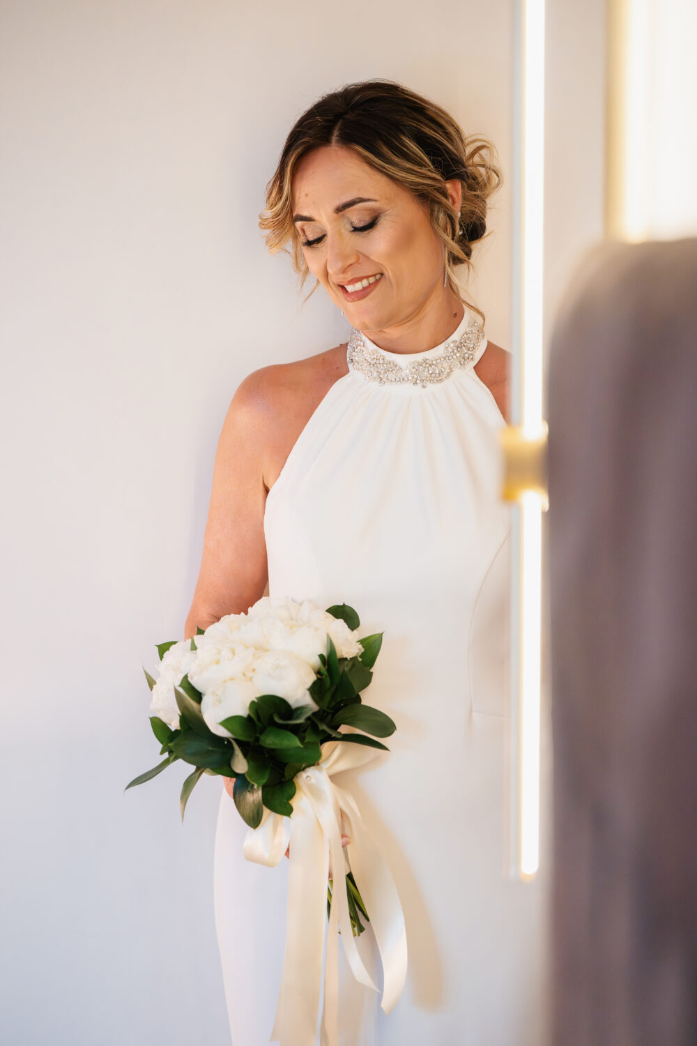 Ritratto sposa sorridente con acconciatura raccolto e bouquet bianco Puglia